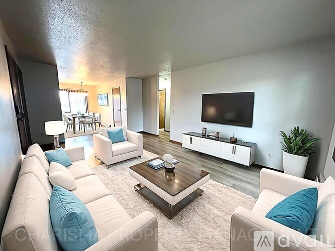 A living room with white furniture and a flat screen TV mounted on the wall.