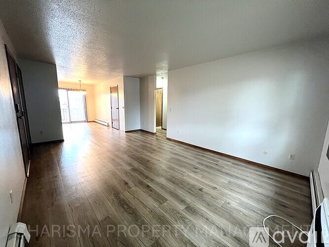 A spacious room with wooden flooring and white walls.
