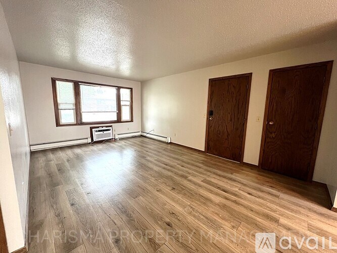 A room with wooden floors and two doors.