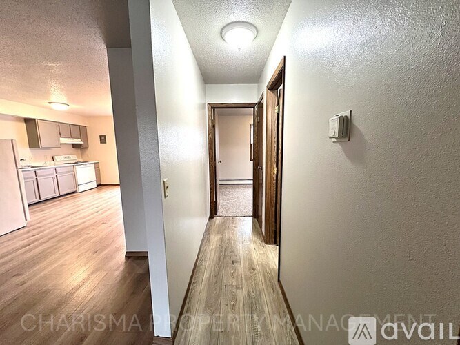 A hallway with a door on the right and a kitchen area on the left.
