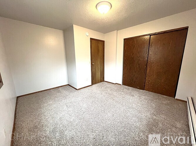 A room with a carpeted floor, a door, and a wall with a light switch.