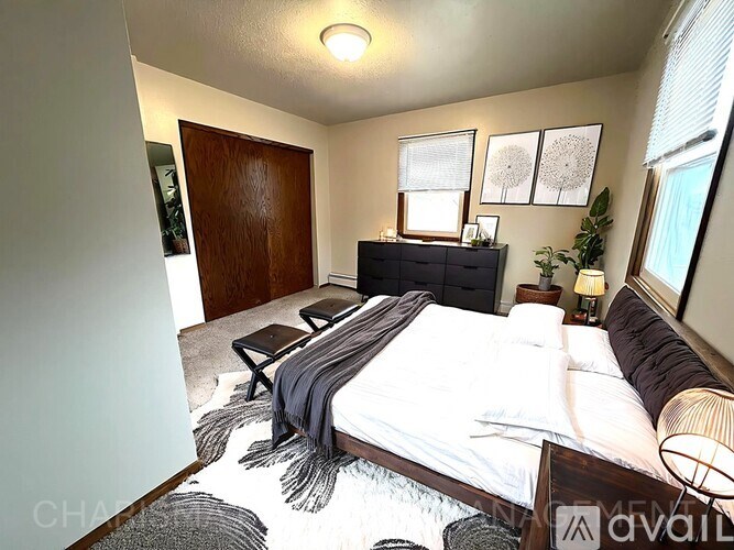 A bedroom with a bed, nightstand, and a plant.