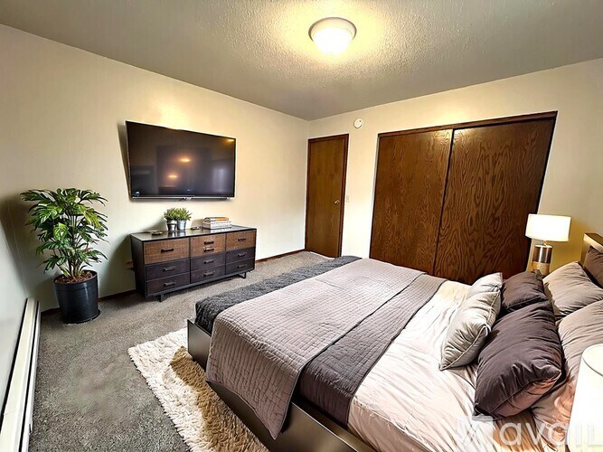 A bedroom with a large bed and a flat screen TV mounted on the wall.