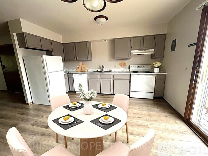 A kitchen with a table set for four with plates and glasses.