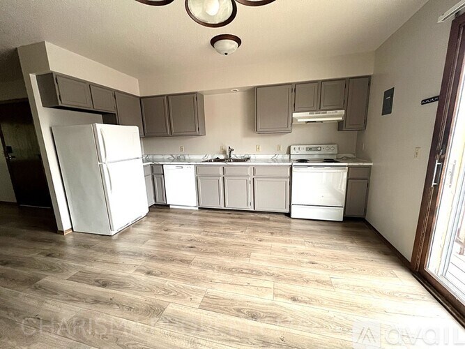 A kitchen with white appliances and wooden floors.