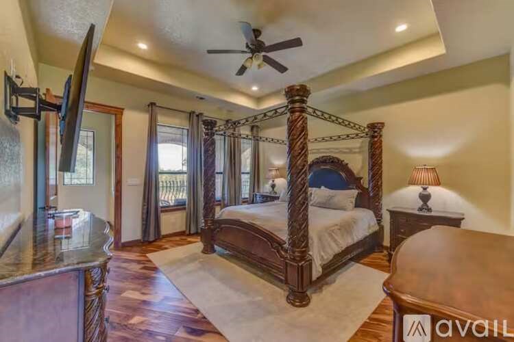 A bedroom with a four poster bed and a ceiling fan.