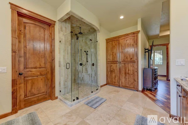 A bathroom with a glass shower stall and wooden doors.
