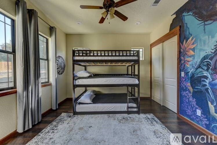 A room with a bunk bed and a ceiling fan.