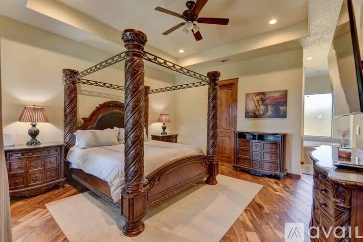 A large bed with a wooden frame is in the center of a room with a ceiling fan.