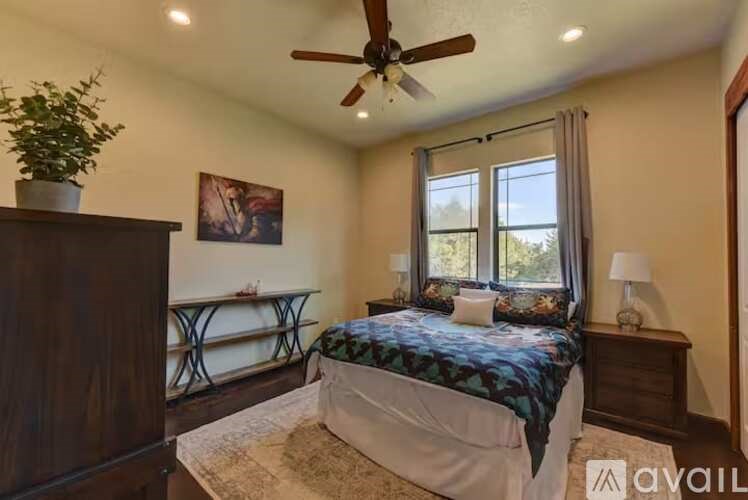 A bedroom with a bed, a ceiling fan, and a window with curtains.