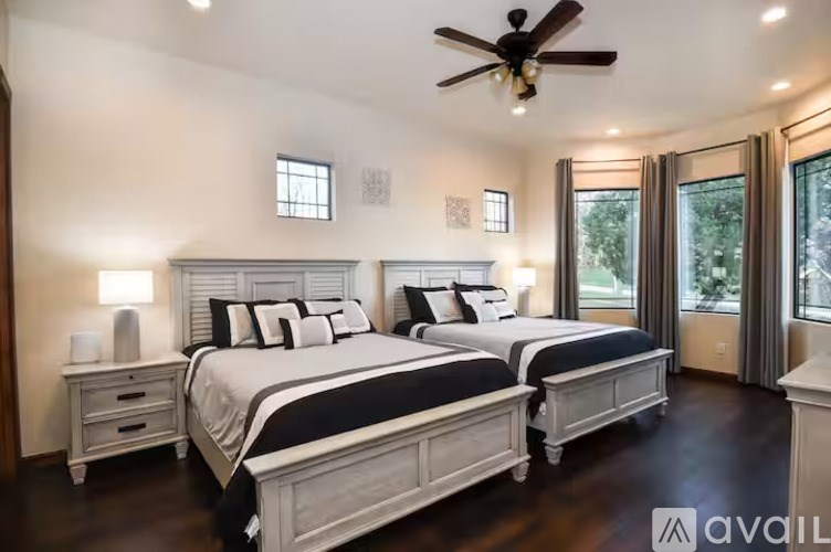 A bedroom with two beds, a ceiling fan, and a window.