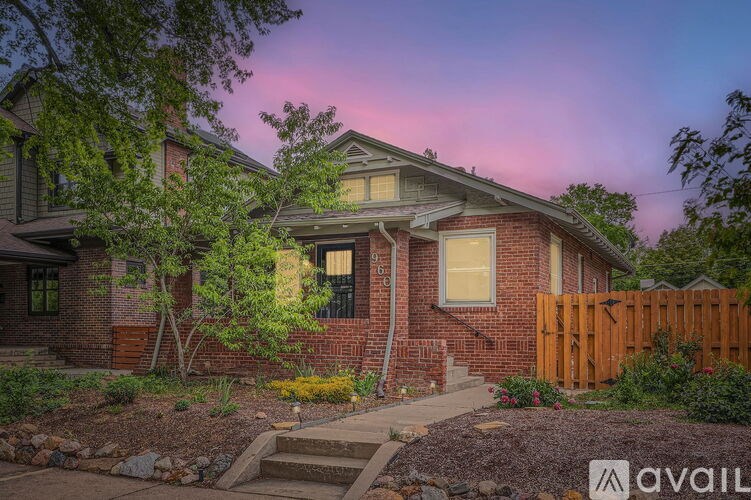 A house with a wooden fence and a tree in front of it.