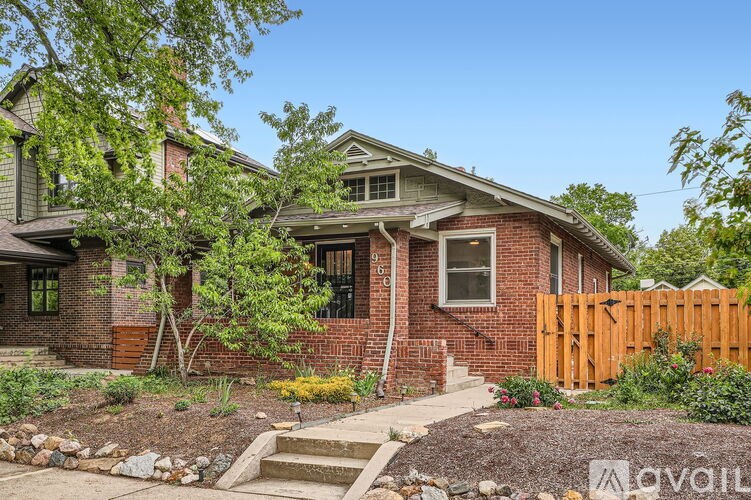 A house with a brown fence and a tree in front of it.