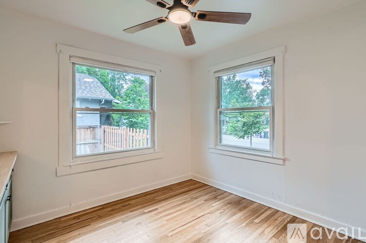 A room with a ceiling fan and two windows.