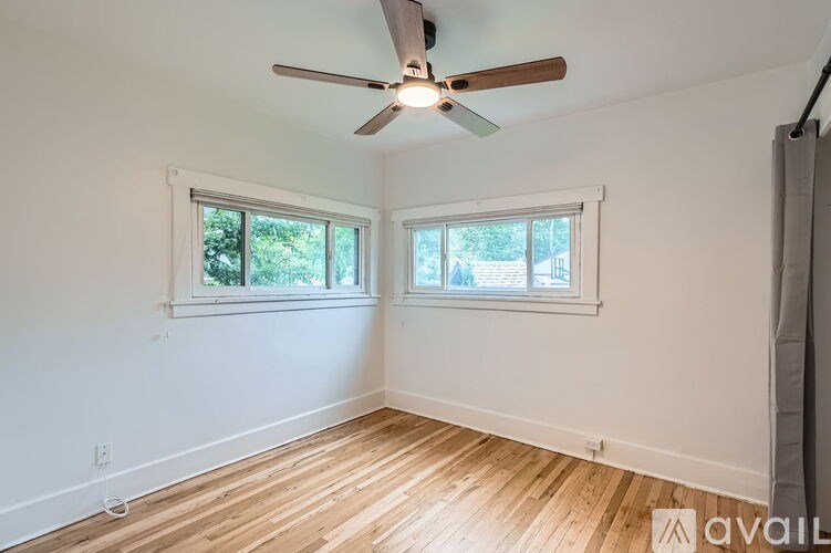 A room with a ceiling fan and two windows.