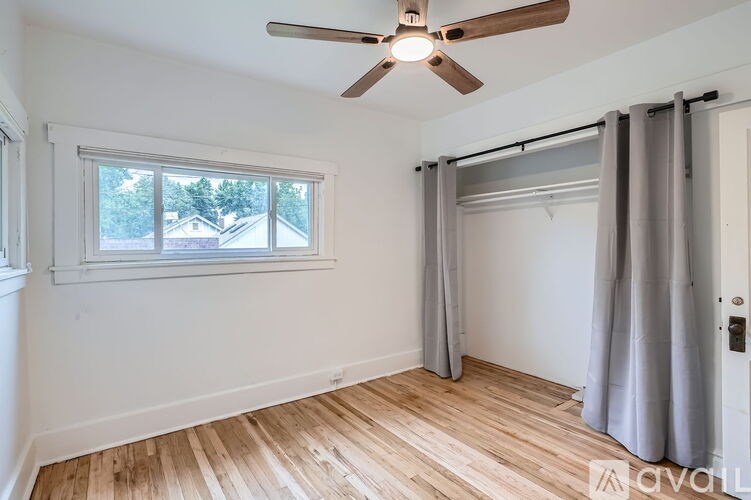 A room with a ceiling fan and a window with curtains.