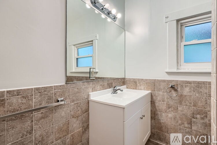 A bathroom with a white cabinet and a mirror above it.