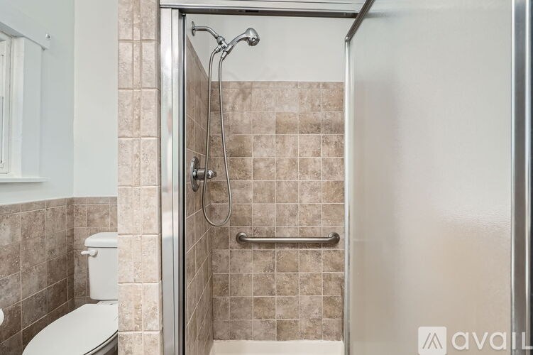 A bathroom with a toilet, a walk-in shower, and a towel bar.