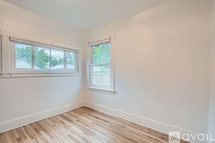 A room with two windows and wooden flooring.