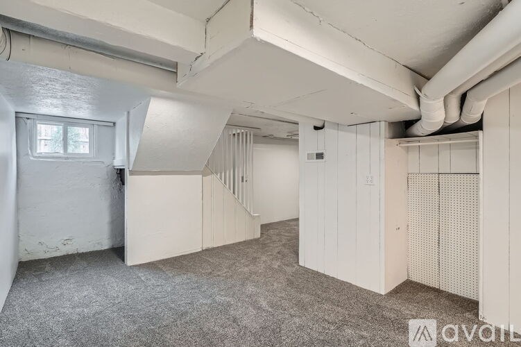 A room with a window, a door, and a wall with pipes.