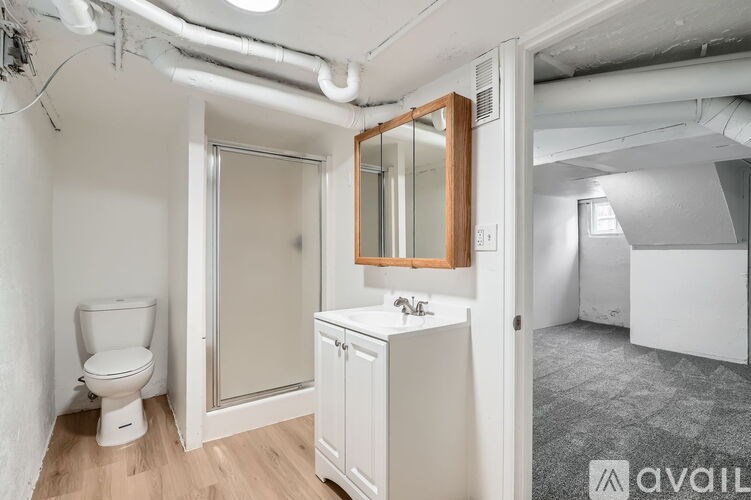 A bathroom with a toilet, sink, and mirror.