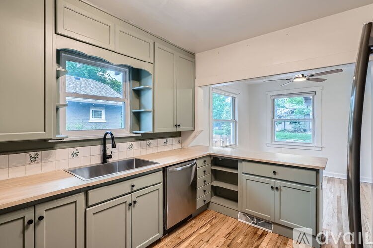 A kitchen with wooden floors and a window overlooking a house.