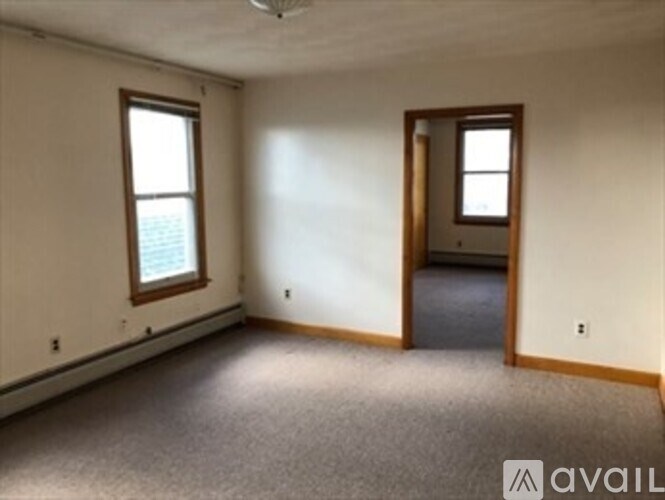 A room with a carpeted floor and two windows.