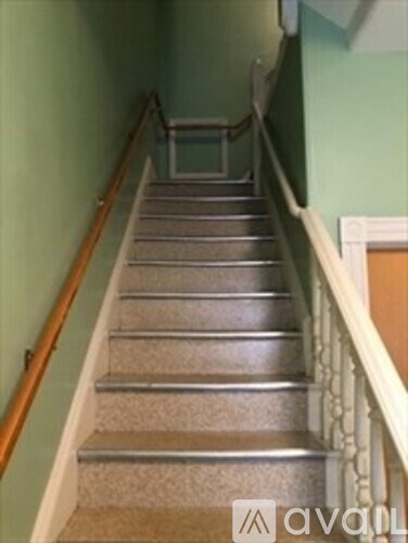 A staircase with a wooden handrail and a carpeted runner.