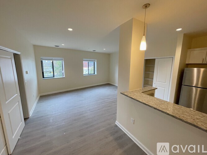 A spacious kitchen and living room with a stainless steel refrigerator and a large island.
