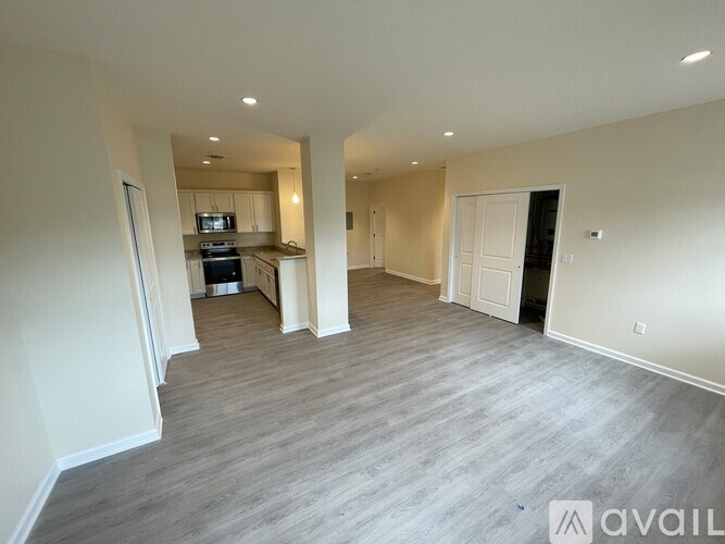 A spacious living room with a kitchen in the background.