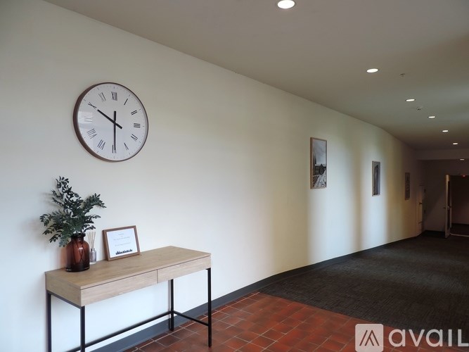 A wall with a clock and a plant on a table.