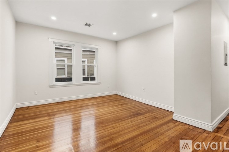 A room with wooden flooring and a window with blinds.