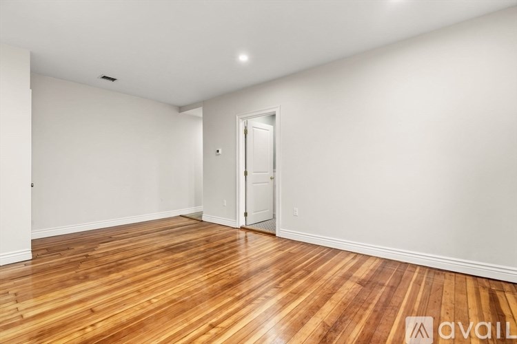 A room with wooden flooring and a white door.