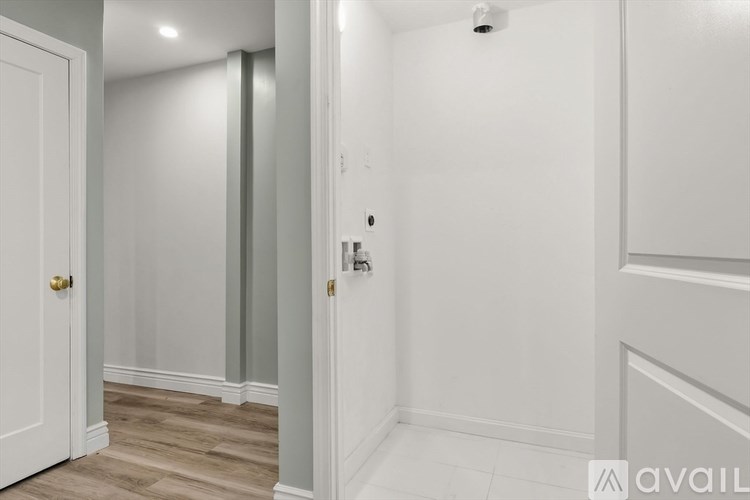 A hallway with a door on the left and a wall-mounted light fixture on the right.