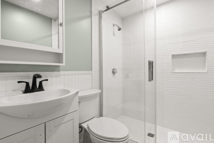 A white bathroom with a toilet, sink, and shower.
