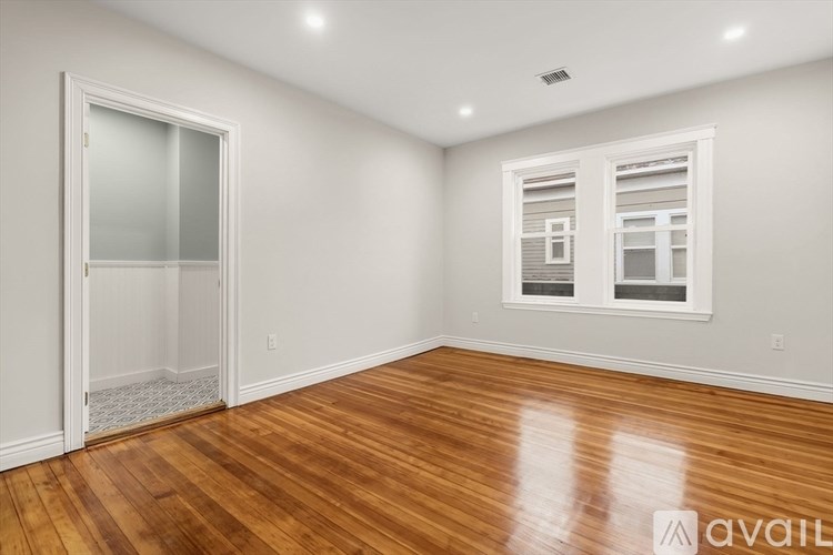 A room with wooden floors and two windows.