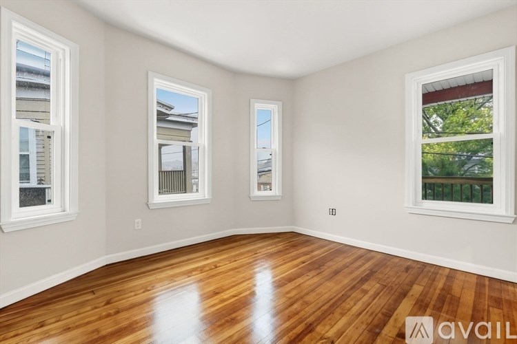A room with wooden floors and three windows.