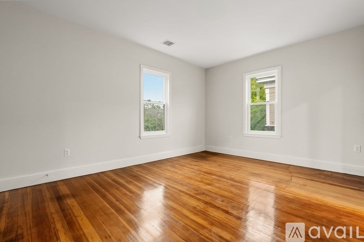A room with wooden floors and two windows.