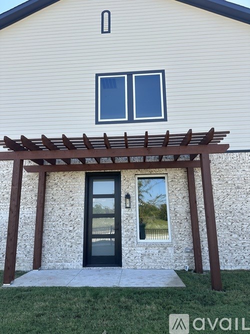 A house with a black door and a pergola above it.