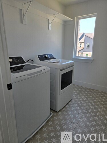 A room with two washing machines and a window.