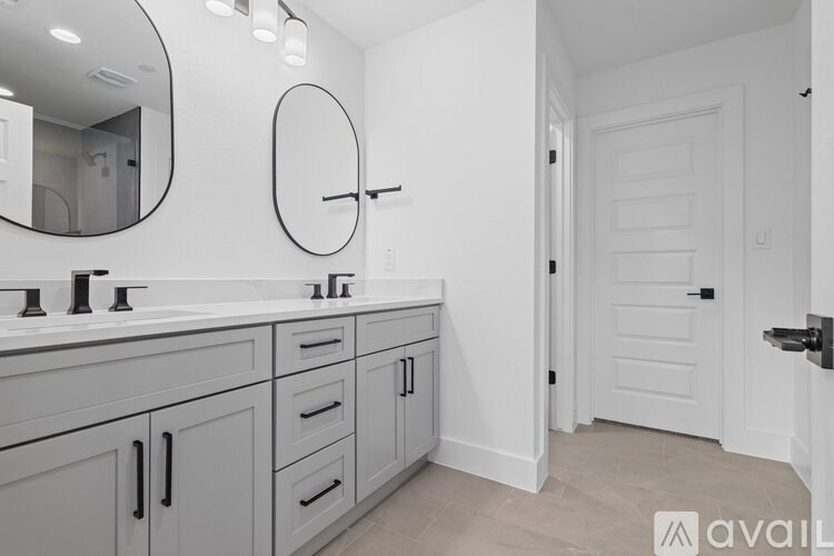 A bathroom with a white door and a round mirror above the sink.