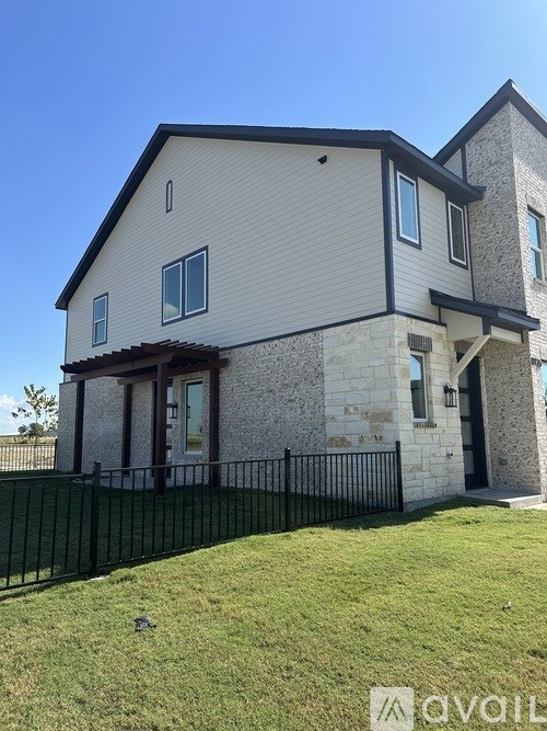 A two-story house with a stone facade and a black metal fence.