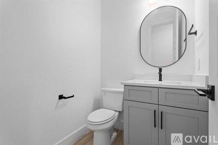 A bathroom with a toilet, sink, and a round mirror.