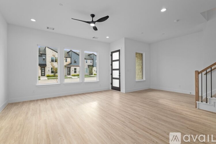 A spacious room with a fan, wooden flooring, and pictures of houses on the wall.