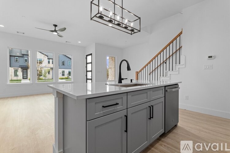 A modern kitchen with a large island and a staircase in the background.