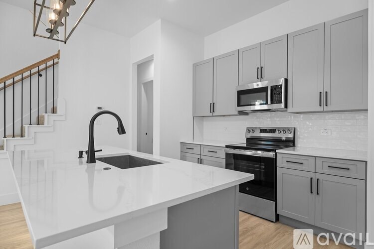 A modern kitchen with a white countertop and grey cabinets.