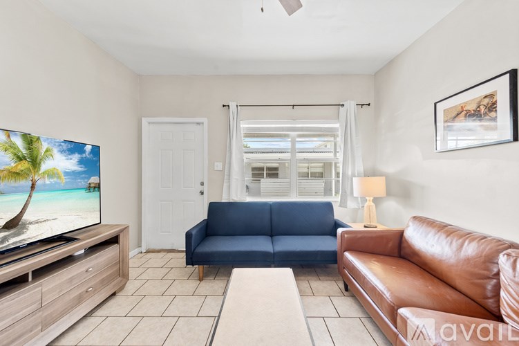A living room with a blue couch and a television displaying a beach scene.