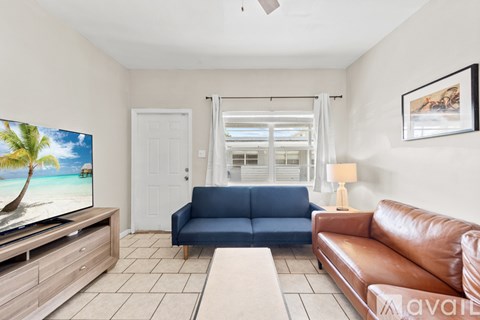 A living room with a blue couch and a television displaying a beach scene.