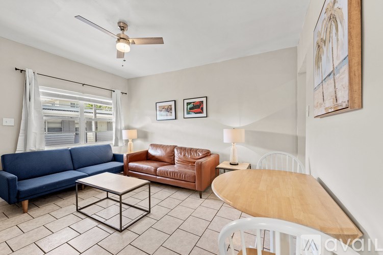 A living room with a blue couch, brown leather chair, and a white coffee table.