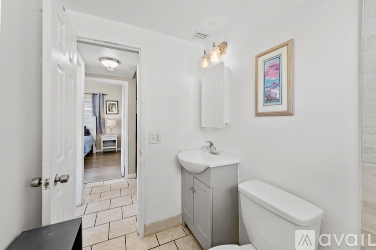 A bathroom with a white tub, sink, and a picture on the wall.